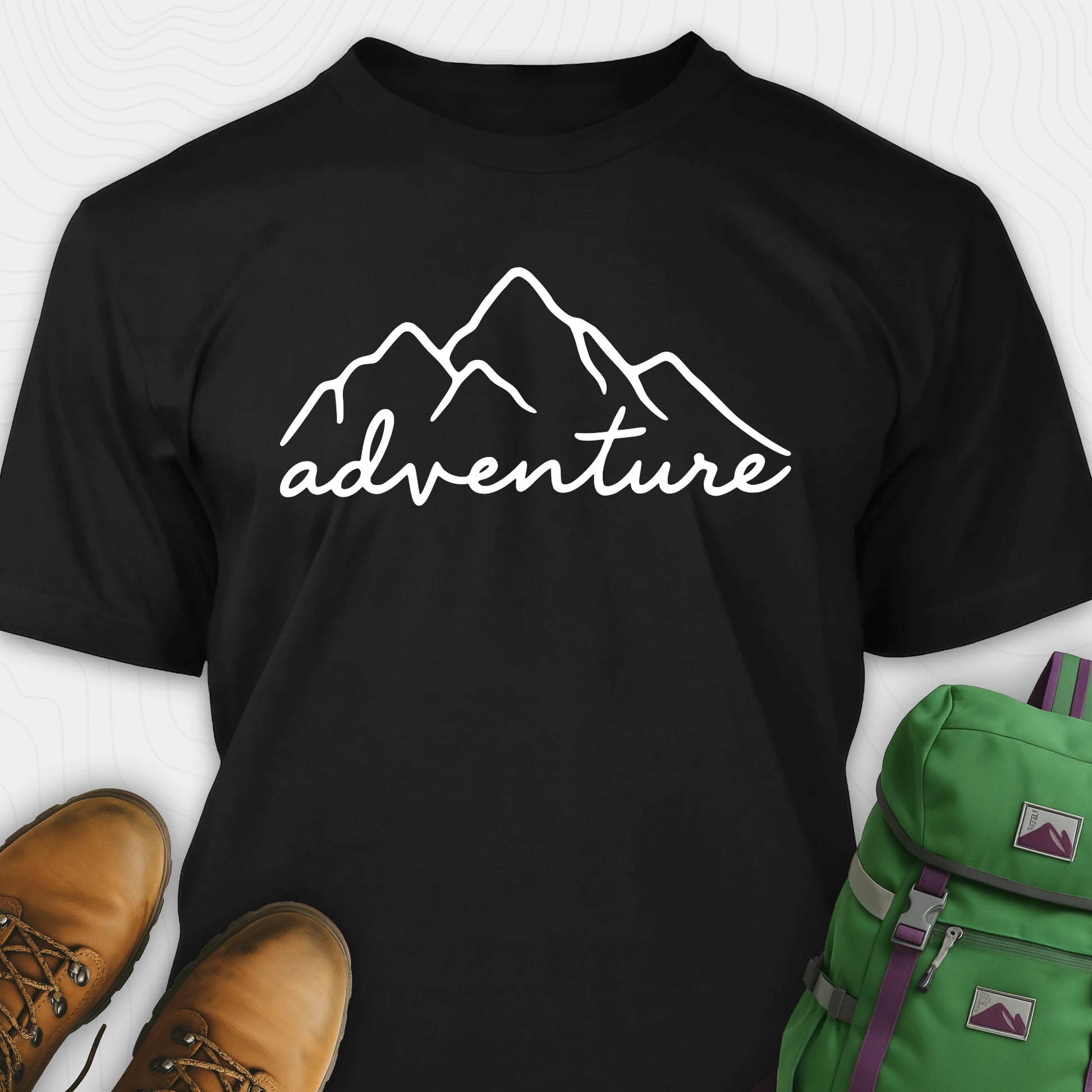 Black adventure shirt with mountain design and 'adventure' text, paired with brown boots and a green backpack.