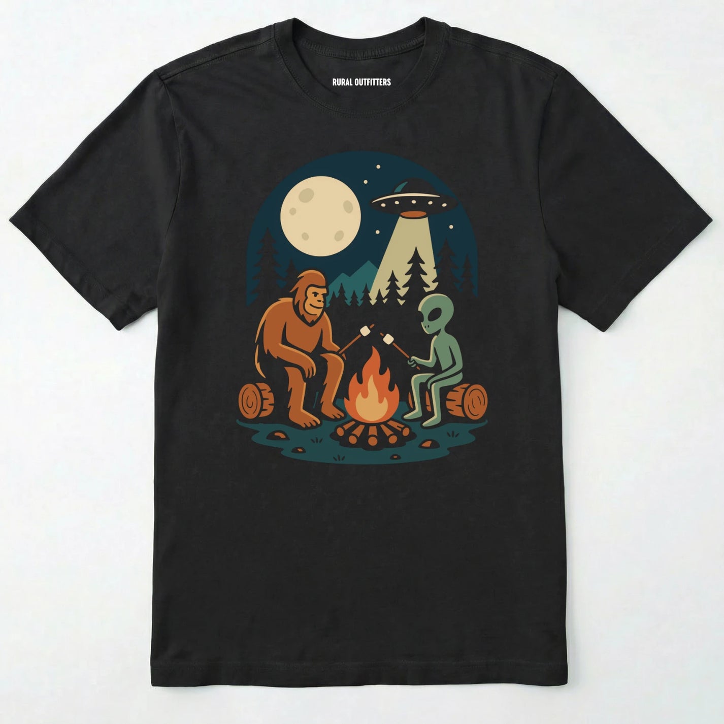 Black bigfoot and alien shirt, featuring a sasquatch and an alien roasting marshmallows around a campfire with moon and ufo graphic on a white background.
