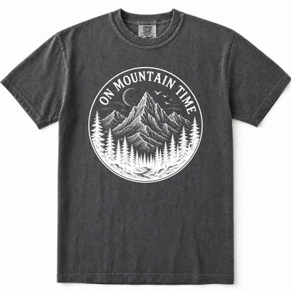 Grey mineral-wash t-shirt with a circular white graphic on the chest depicting a mountain, pine trees, and a crescent moon with the text 'ON MOUNTAIN TIME'.