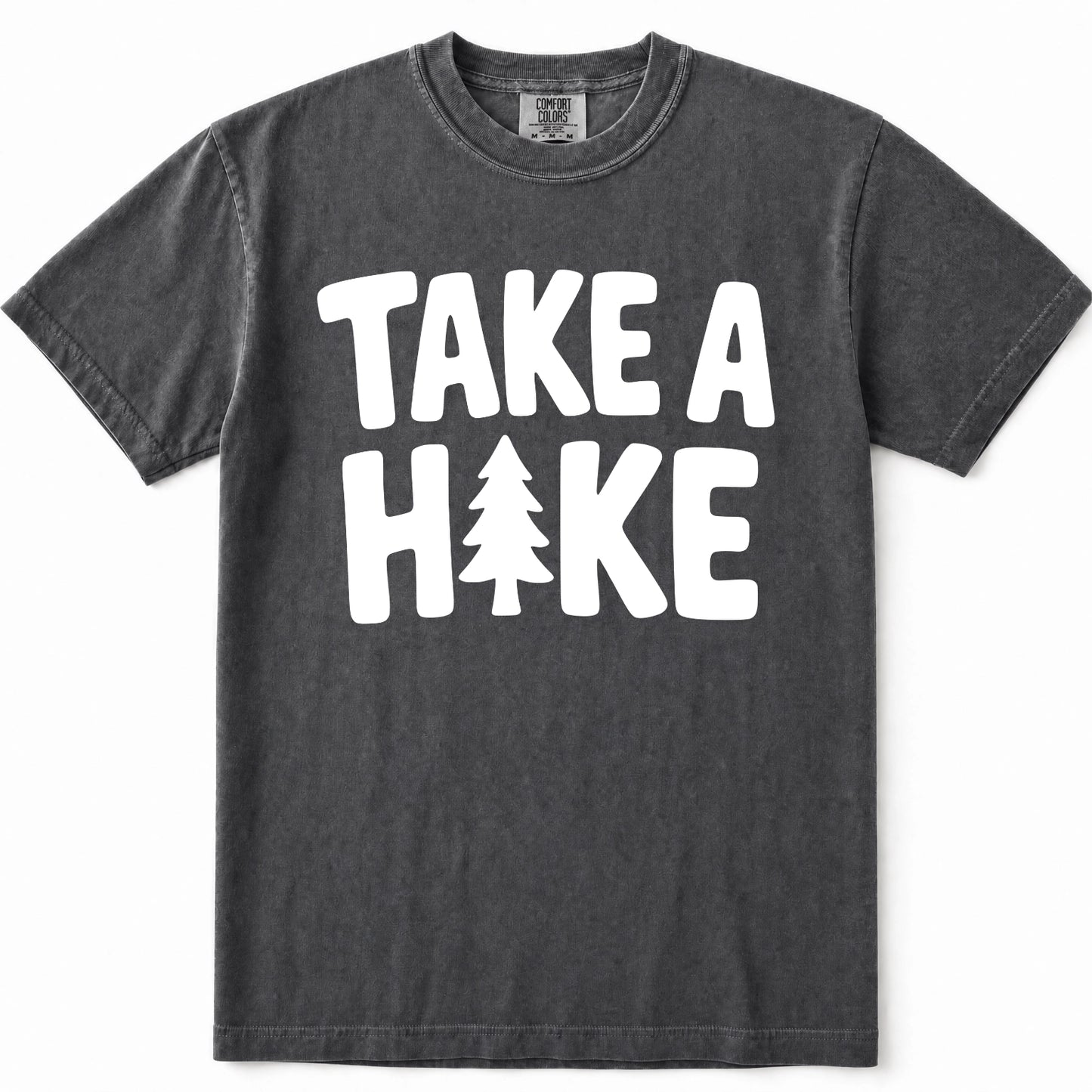Pepper mineral-wash t-shirt with a bold white graphic print reading 'TAKE A HIKE' where the letter 'I' is replaced by a pine tree silhouette. The shirt is displayed flat against a clean white background.