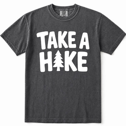 Pepper mineral-wash t-shirt with a bold white graphic print reading 'TAKE A HIKE' where the letter 'I' is replaced by a pine tree silhouette. The shirt is displayed flat against a clean white background.