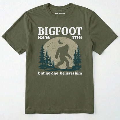 Military Green bigfoot saw me shirt with a vintage outdoor sasquatch in the forest graphic on a white background.