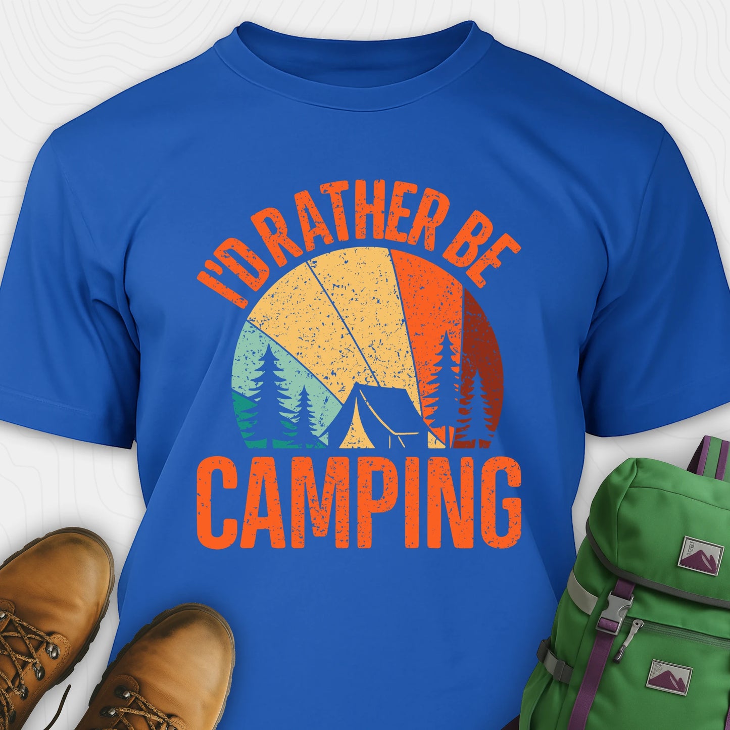 Blue t-shirt with 'I'd Rather Be Camping' design, boots, and backpack on a white background