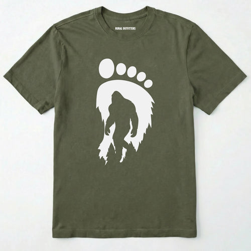 Military Green bigfoot t-shirt with cryptid-themed footprint graphic and sasquatch silhouette on a white background.