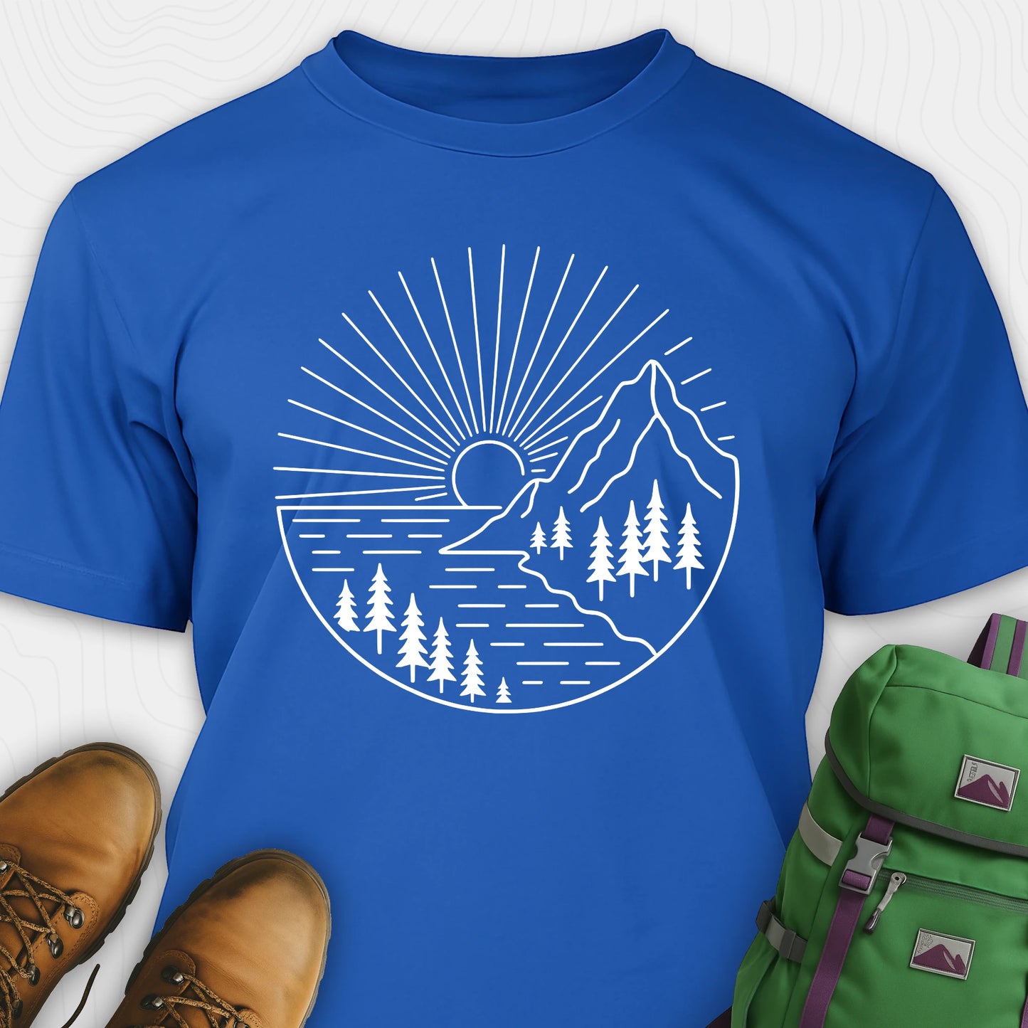 Royal blue mountain t-shirt with a white line-art design of mountains, trees, and a sunrise.