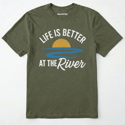 Military Green river shirt with 'life is better at the river' design, paired with brown boots and a green backpack on a light grey background.