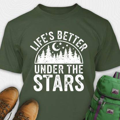 Military green Life's Better Under the Stars t-shirt with forest and moon graphic, paired with brown boots and a green backpack on a white background.