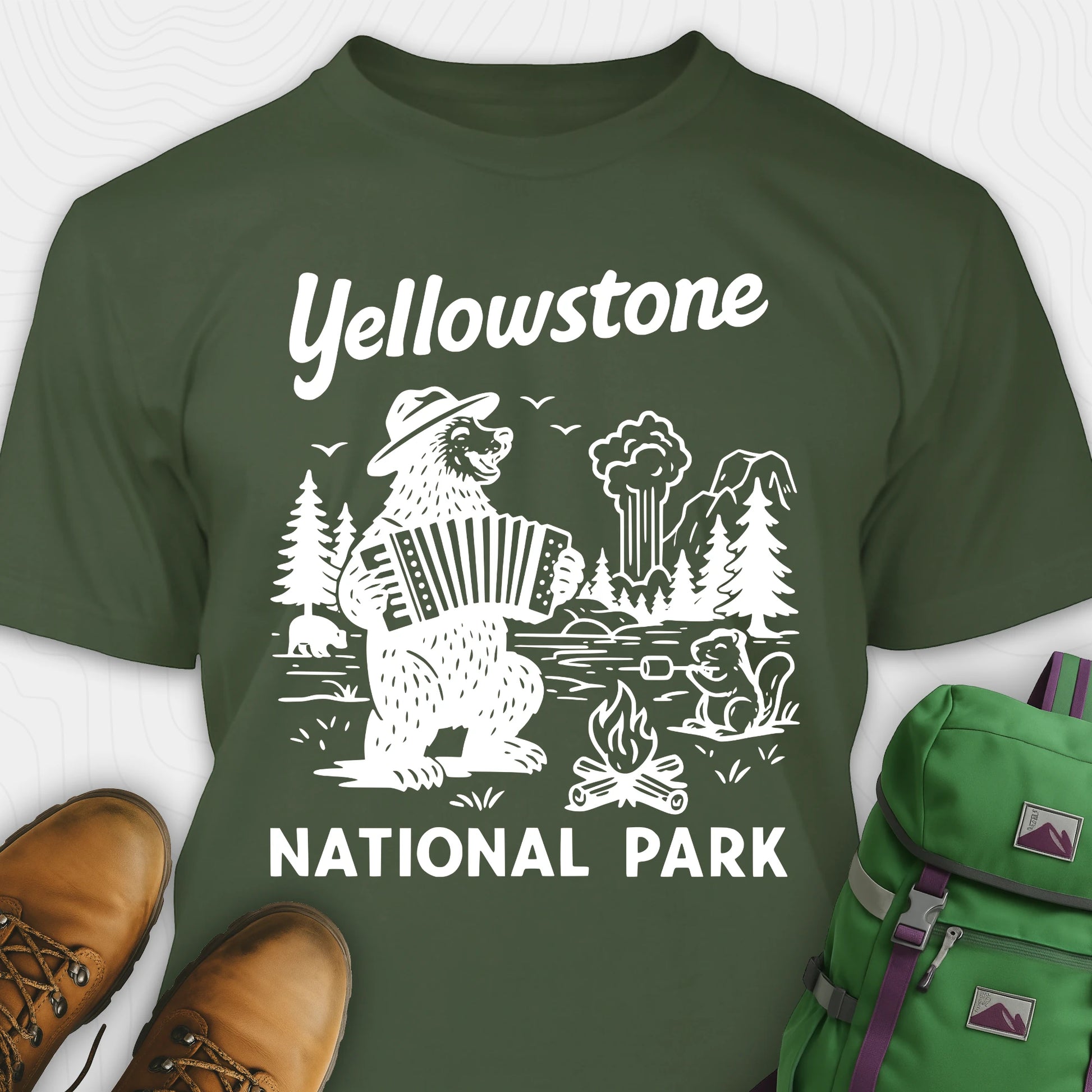 Military green t-shirt with a brown bear playing an accordion and “Yellowstone National Park” text, styled with hiking boots and a green backpack.