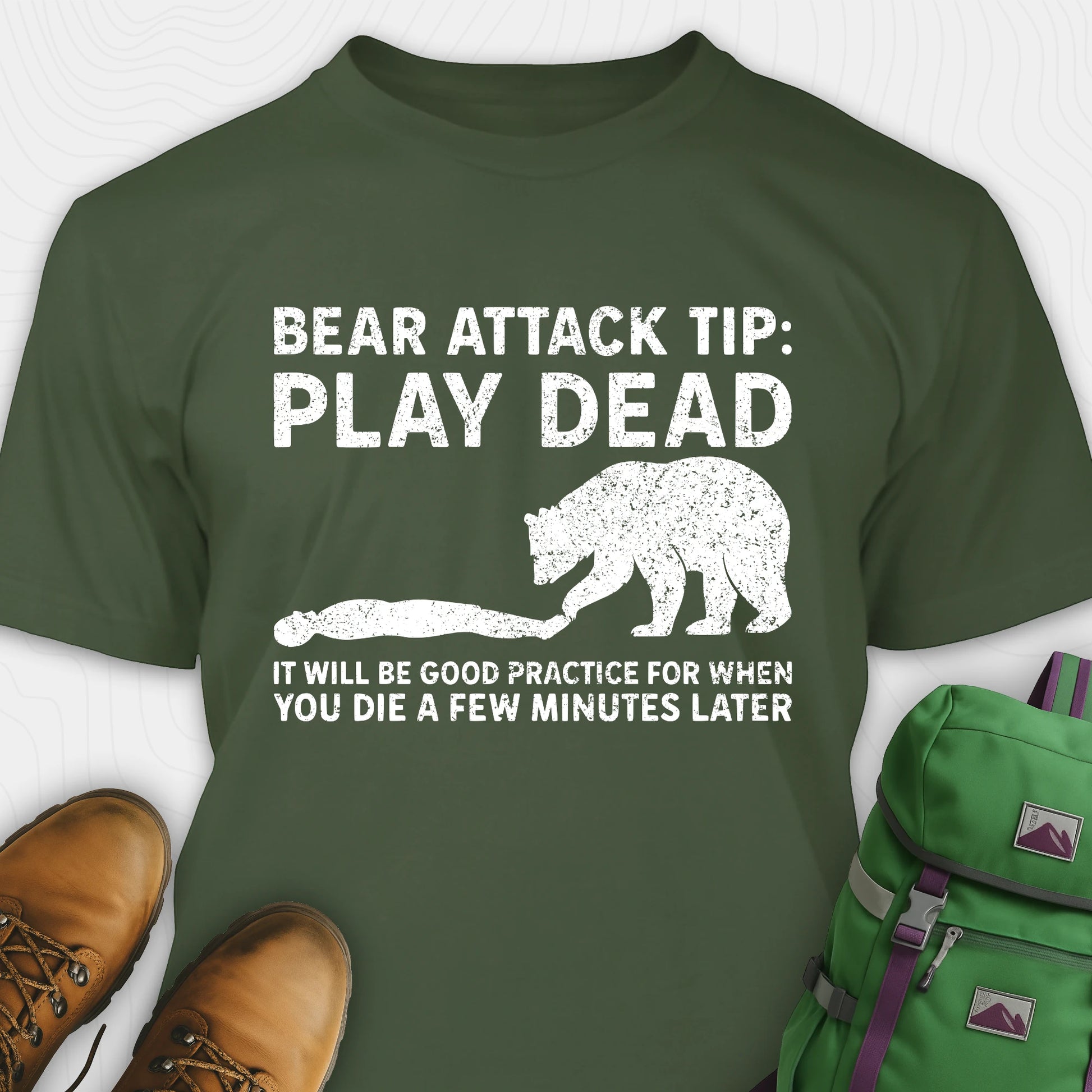 Green bear tee shirt with bear attack tip graphic and text, paired with brown boots and a green backpack.