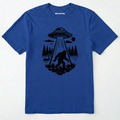 Royal monster shirt with Bigfoot, a forest scene, and a UFO beam graphic on a white background.
