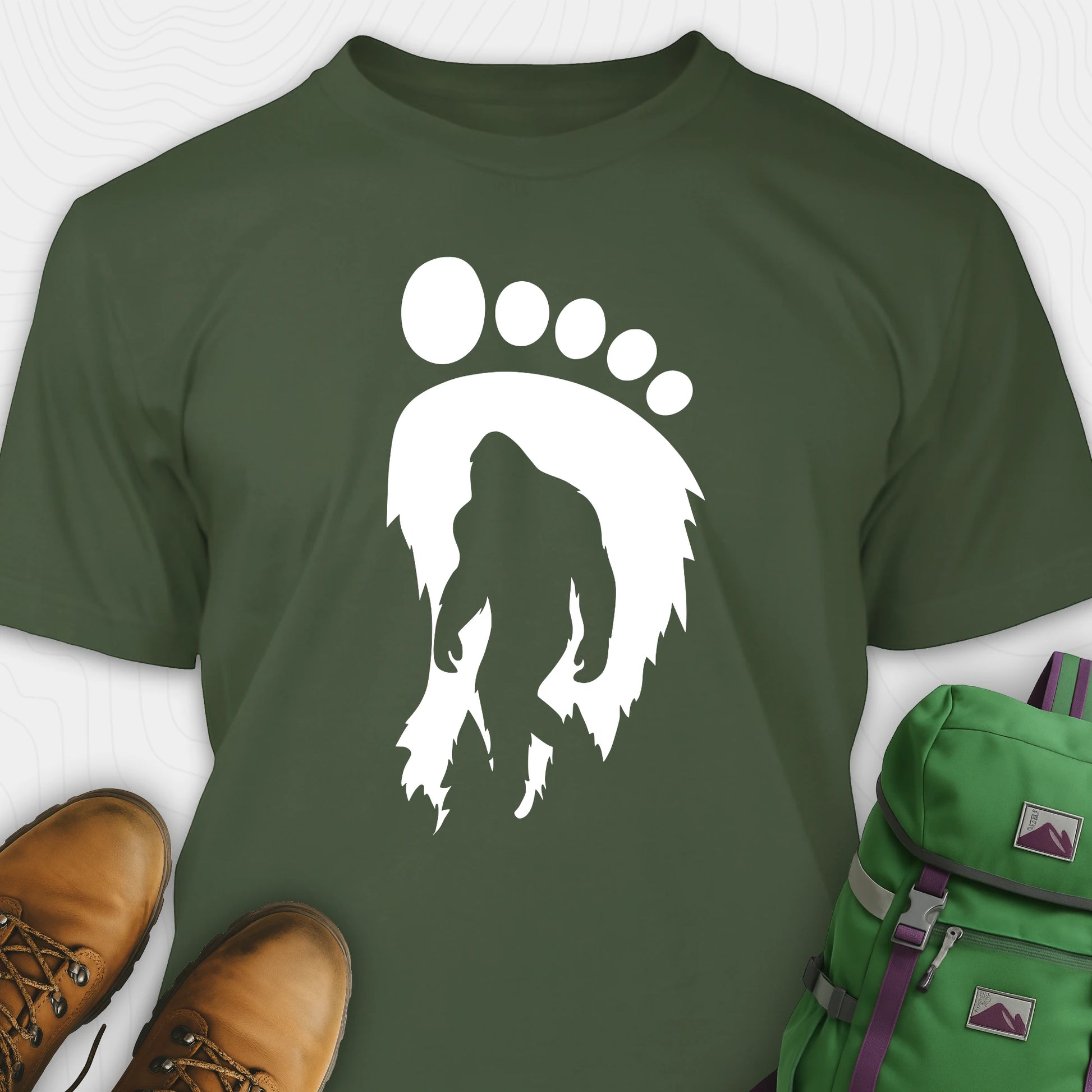 Green bigfoot t-shirt with cryptid themed footprint graphic and sasquatch silhouette