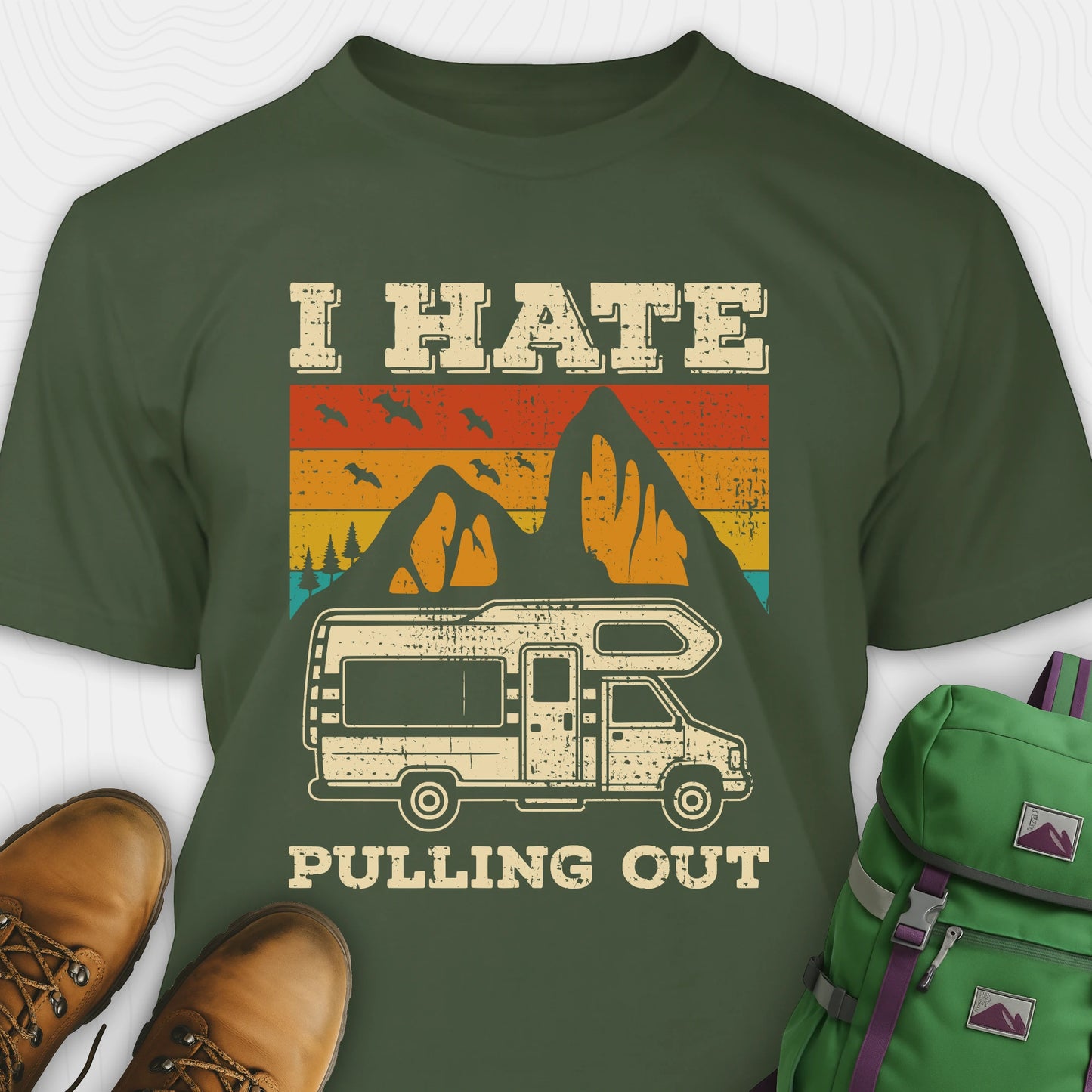 Green I hate pulling out shirt with a graphic design of an RV and mountains, displayed with brown boots and a green backpack.