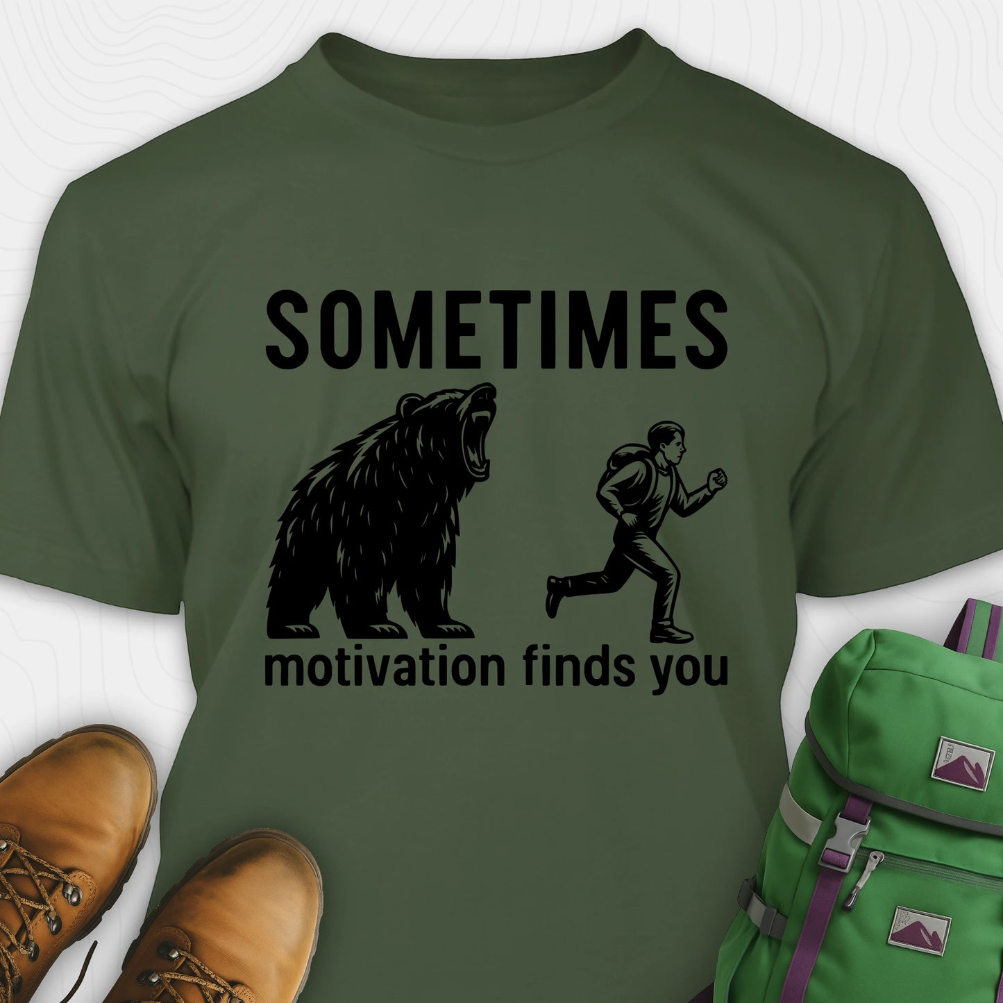 Green motivational t-shirt with bear and person graphic and text 'Sometimes motivation finds you' on a white background.