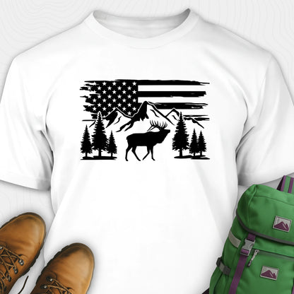 White deer t-shirt with black graphic design of an American flag, trees, and a moose, accompanied by brown boots and a green backpack.