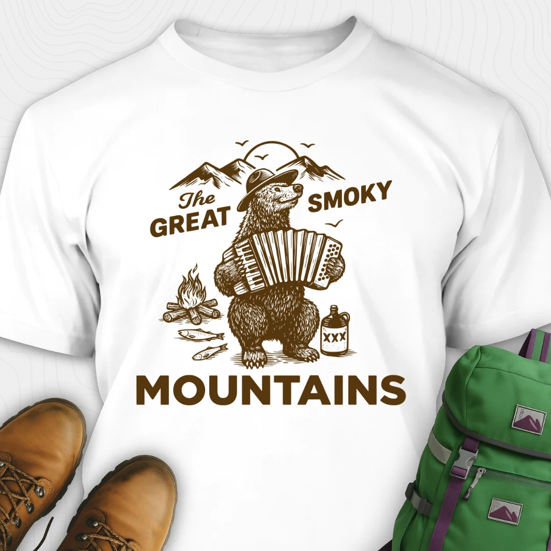 White t-shirt with bear playing accordion graphic and 'The Great Smoky Mountains' text, paired with hiking boots and a green backpack.