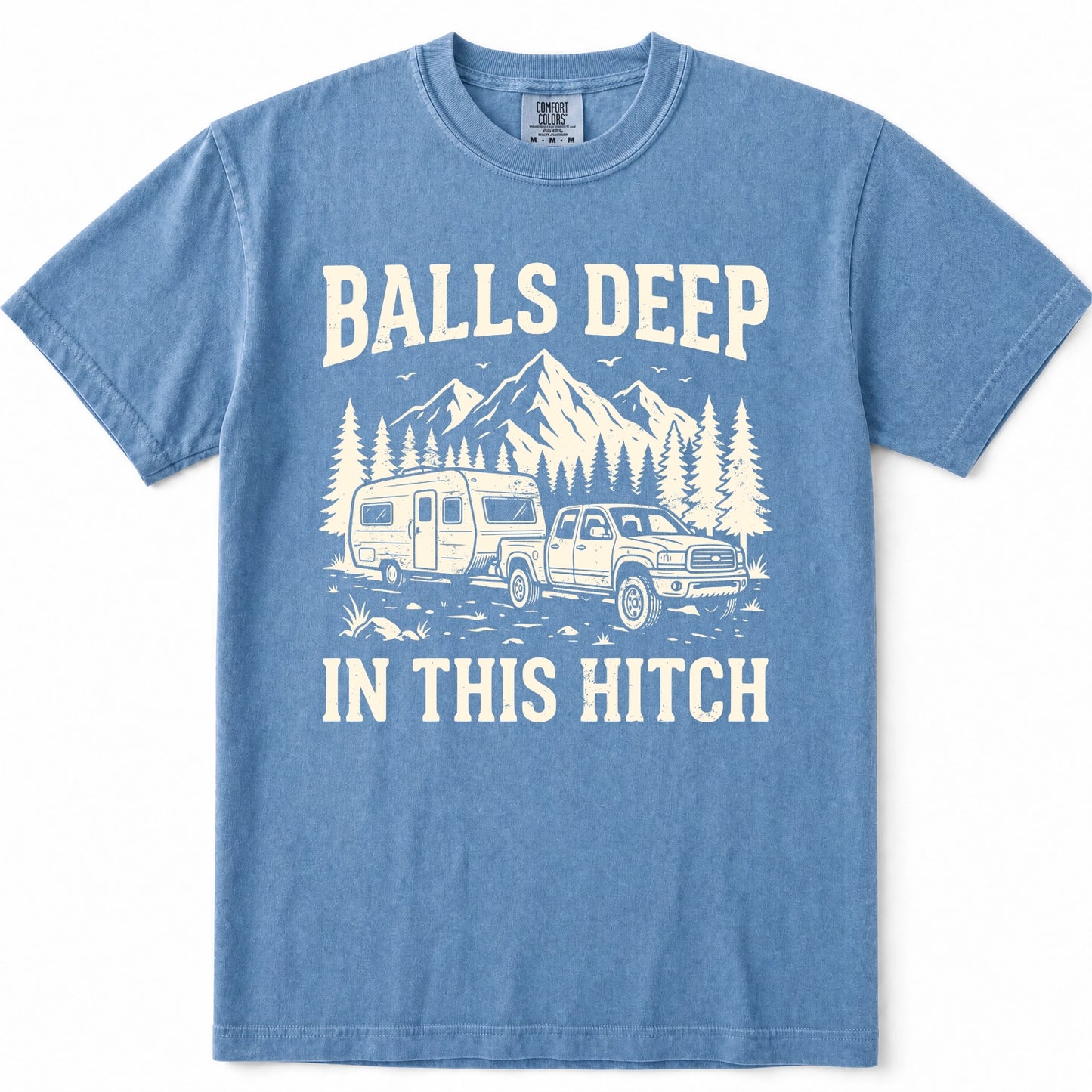 Blue Jean short-sleeve t-shirt with a vintage-style cream graphic print featuring the text 'BALLS DEEP IN THIS HITCH' and an illustration of a pickup truck towing a travel trailer in front of mountains and pine trees.