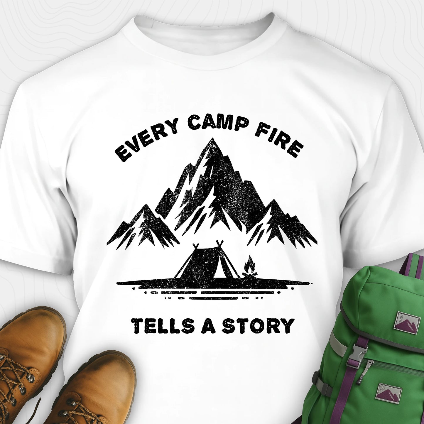 White campfire story shirt with mountains and tent graphic and "every camp fire tells a story" text