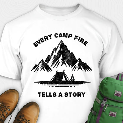 White campfire story shirt with mountains and tent graphic and "every camp fire tells a story" text