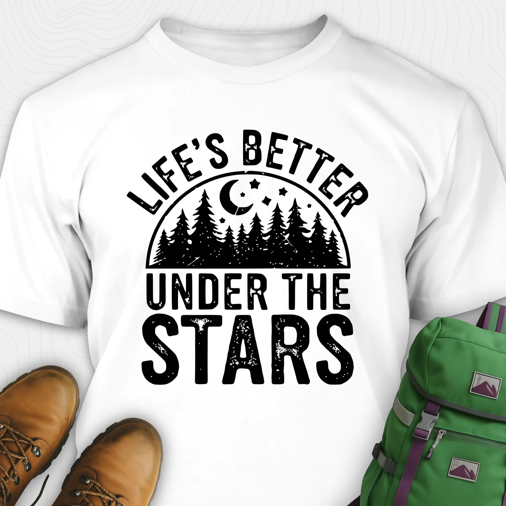 White Life's Better Under the Stars t-shirt with forest and moon graphic, paired with brown boots and a green backpack on a white background.