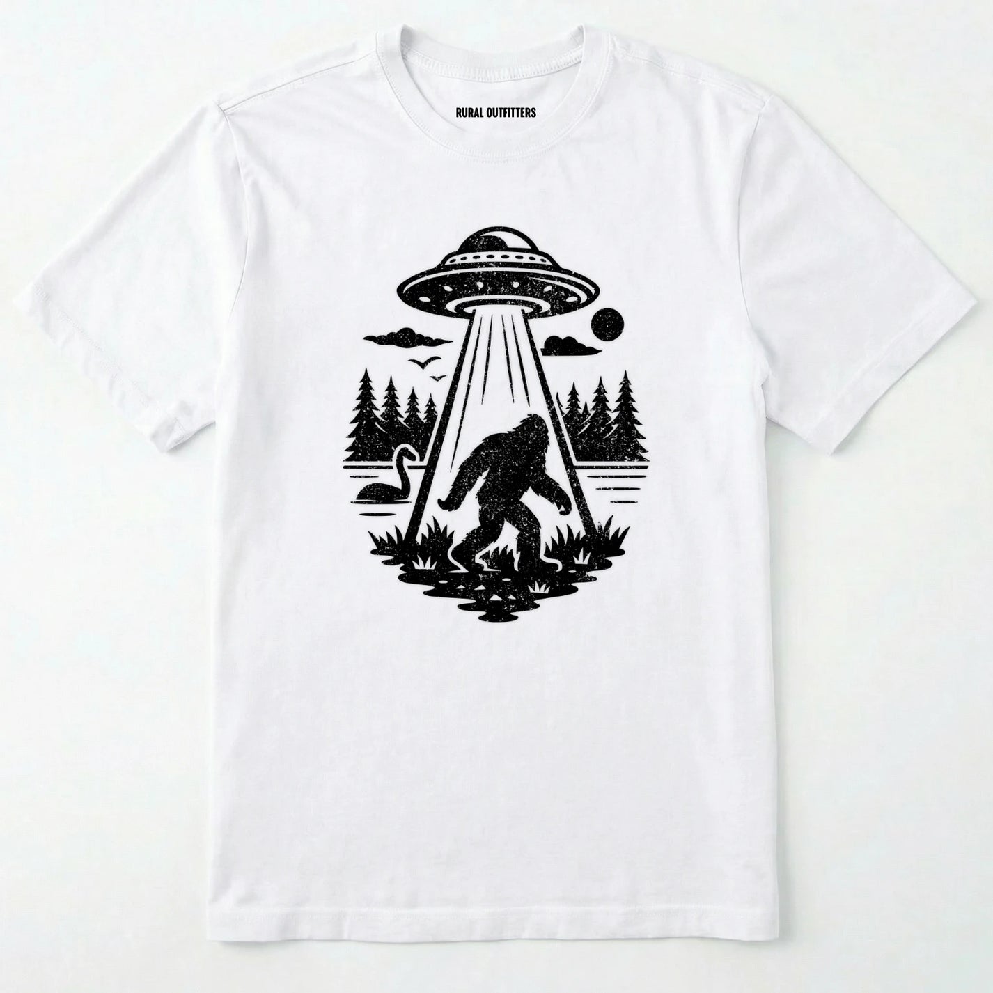 White monster shirt with Bigfoot, a forest scene, and a UFO beam graphic on a white background.