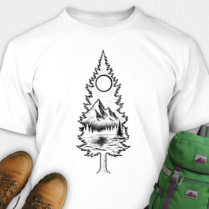 A white tree t-shirt featuring a detailed white graphic of a pine tree silhouette. The tree outline contains a landscape scene: a mountain peak rising over a forested shoreline, with its reflection visible in a lake below. Above the mountain is a starry night sky and a full or partial circle representing the moon or sun. The t-shirt is displayed flat with brown leather boots to the lower left and a green and purple backpack to the lower right, suggesting an outdoor or hiking theme.