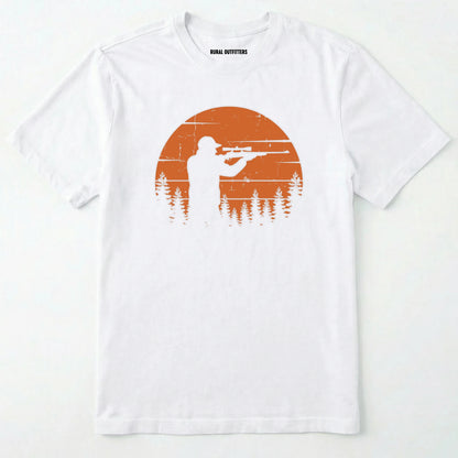 White t-shirt with a graphic of a person holding a rifle and trees, on an orange background, on a white background.