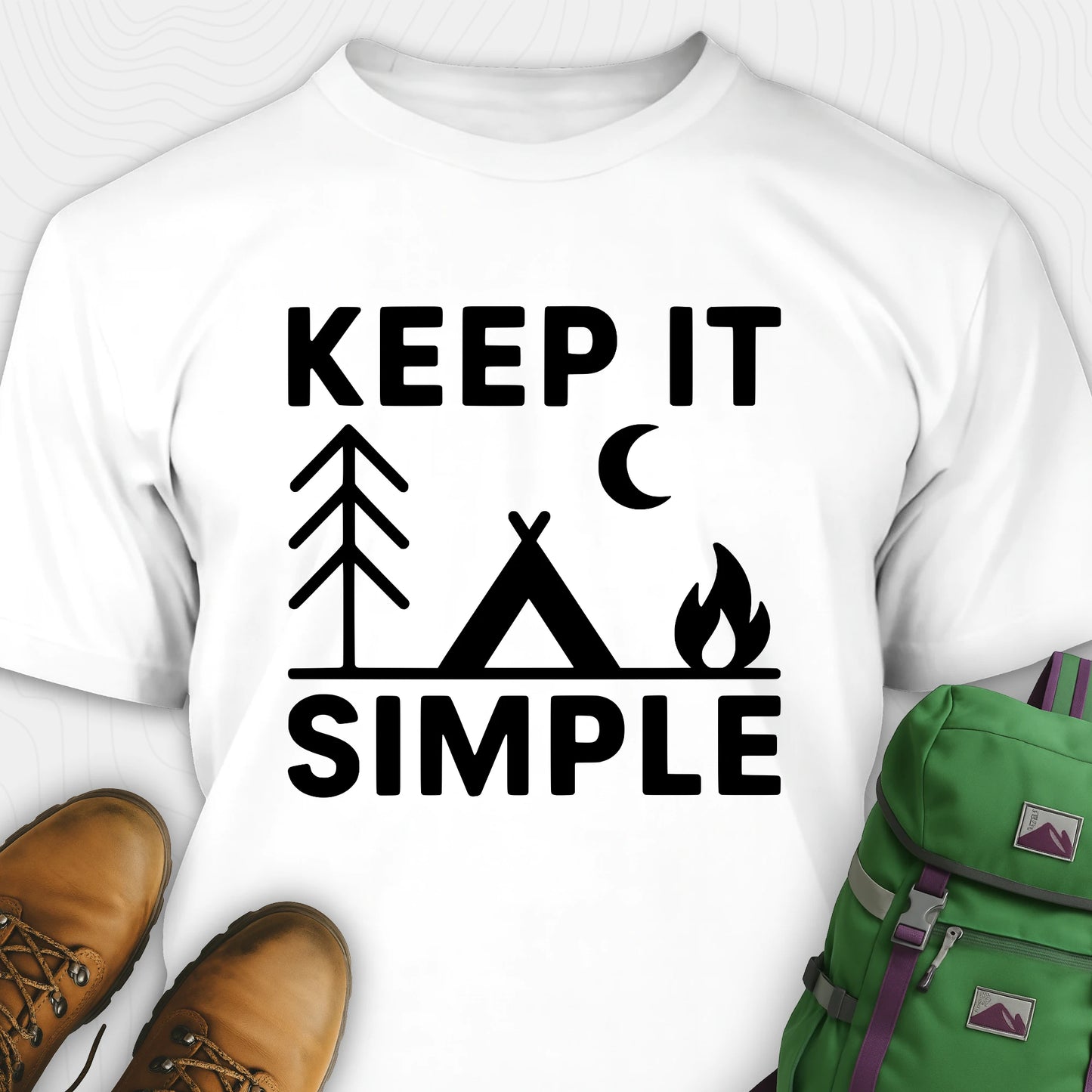 White keep it simple camping t-shirt with tent and campfire graphic with boots, and a backpack on either side on a white background