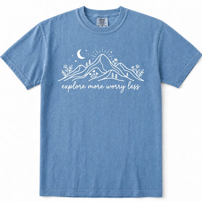 Blue Jean short-sleeve t-shirt with a white graphic of mountains, a crescent moon, stars, and the text 'explore more worry less' printed on the chest, displayed flat against a white background.