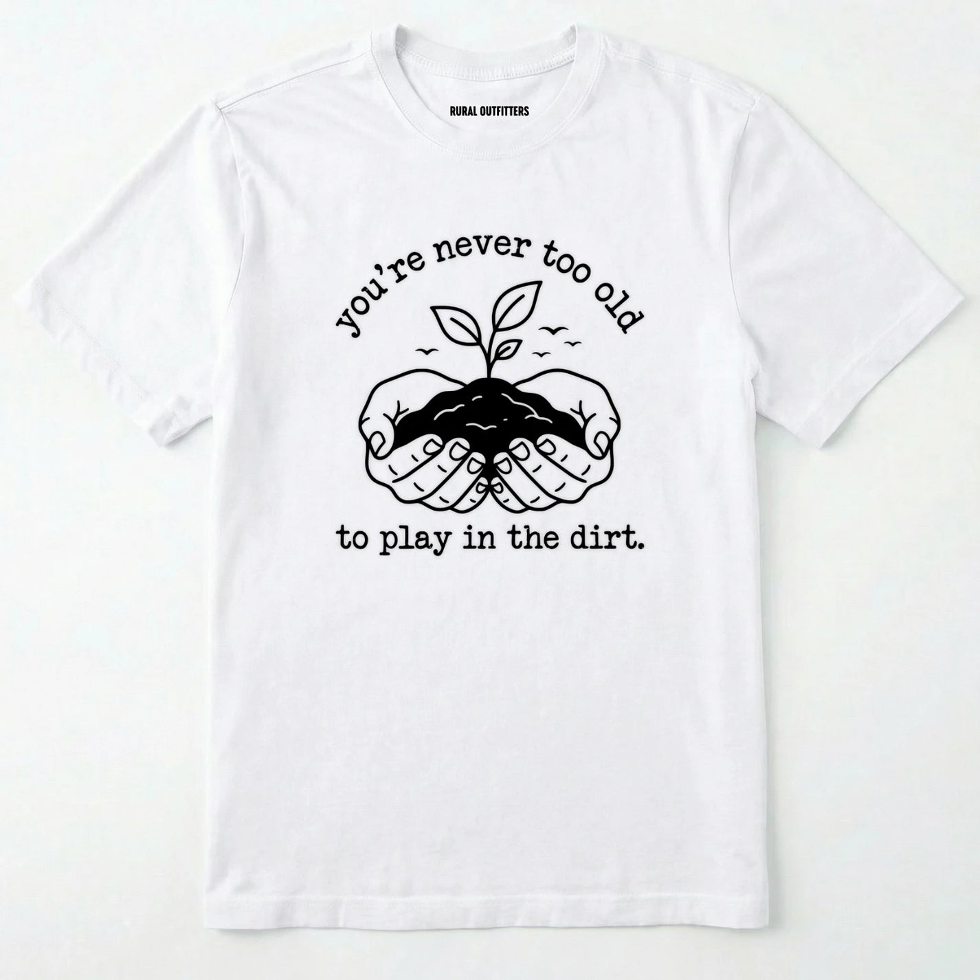 White t-shirt with black graphic and text 'you're never too old to play in the dirt' on a white background