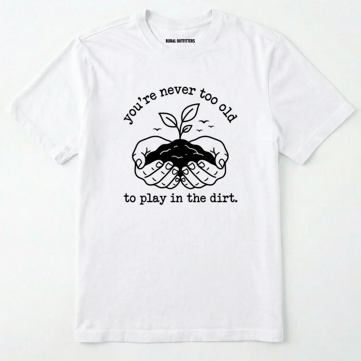 White t-shirt with black graphic and text 'you're never too old to play in the dirt' on a white background