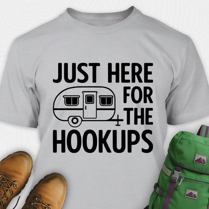 Grey hook ups t-shirt with trailer graphic and funny camping quote, paired with brown boots and a green backpack on a white background.