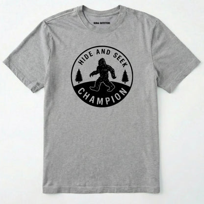 Sport Grey bigfoot hide and seek champion shirt with forest emblem on a white background.