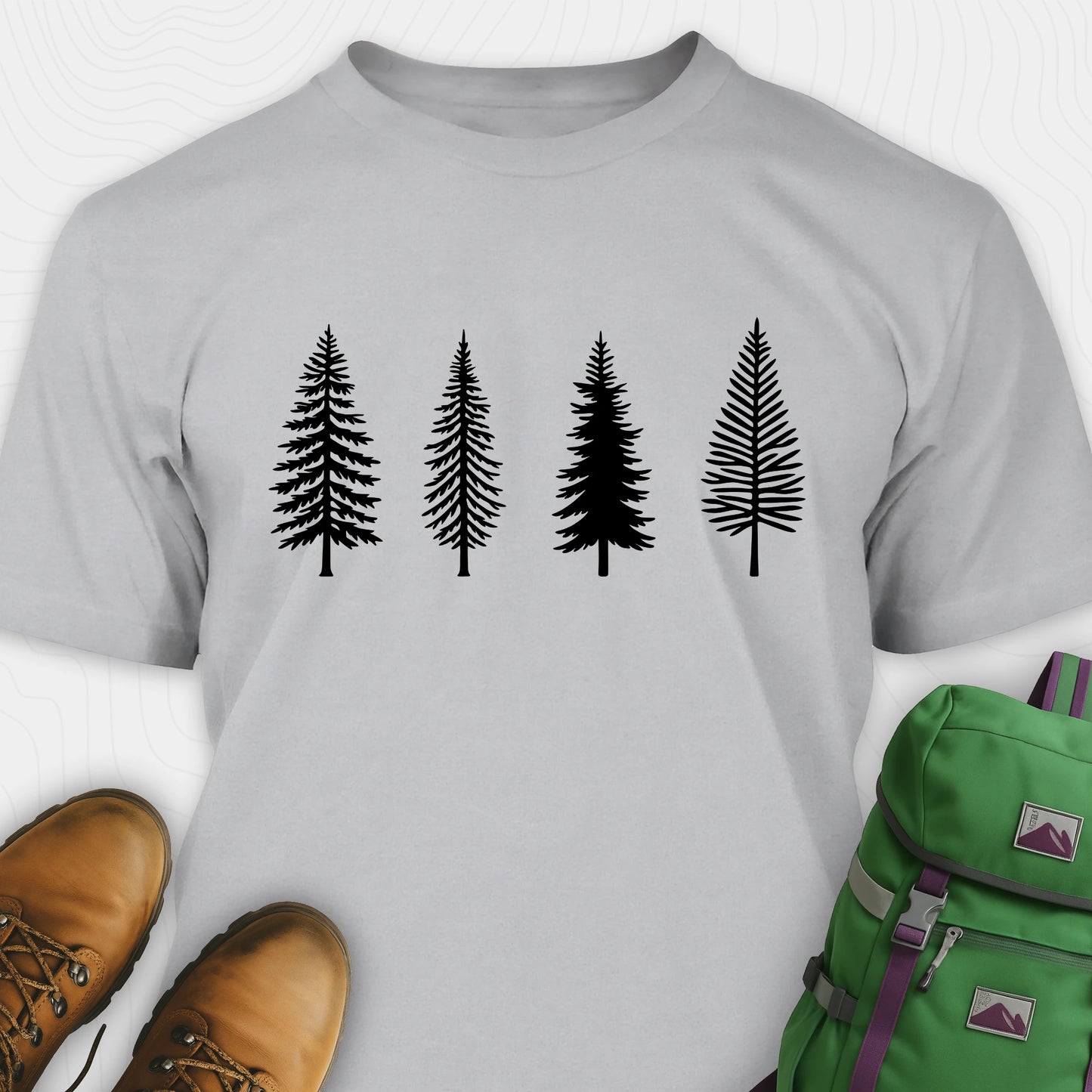 Sport grey pine tree shirt with black minimalist forest graphic, brown boots, and a green backpack on a light gray background