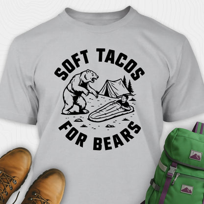 Sport Grey funny bear shirt with bear graphic and text 'Soft Tacos for Bears' on a white background. surrounded by hiking boots and a green backpack.