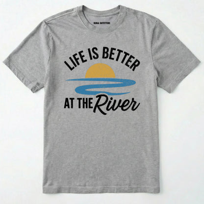Sport Grey river shirt with 'life is better at the river' design, paired with brown boots and a green backpack on a light grey background.