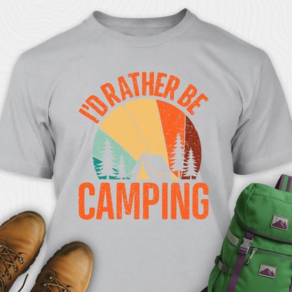 Gray t-shirt with 'I'd Rather Be Camping' design, brown boots, and green backpack on a white background