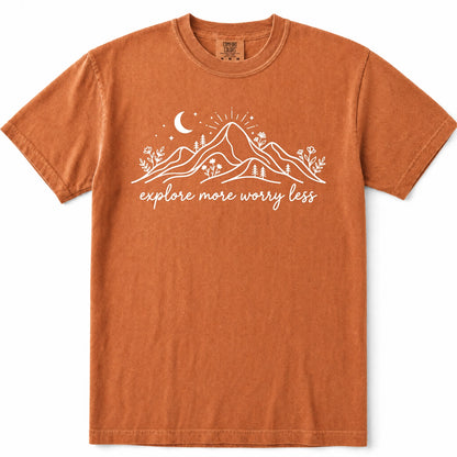 Yam burnt orange crewneck t-shirt with a white graphic of mountains, a crescent moon, and the text 'explore more worry less' printed on the chest, displayed flat against a white background.