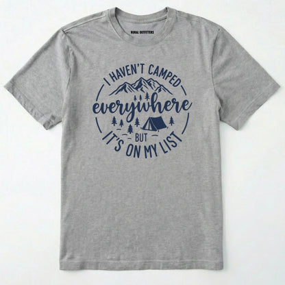 Sport Grey funny camping shirt saying with mountains, trees, tent graphic and "I Haven't Camped Everywhere But It's On My List" text on a white background.
