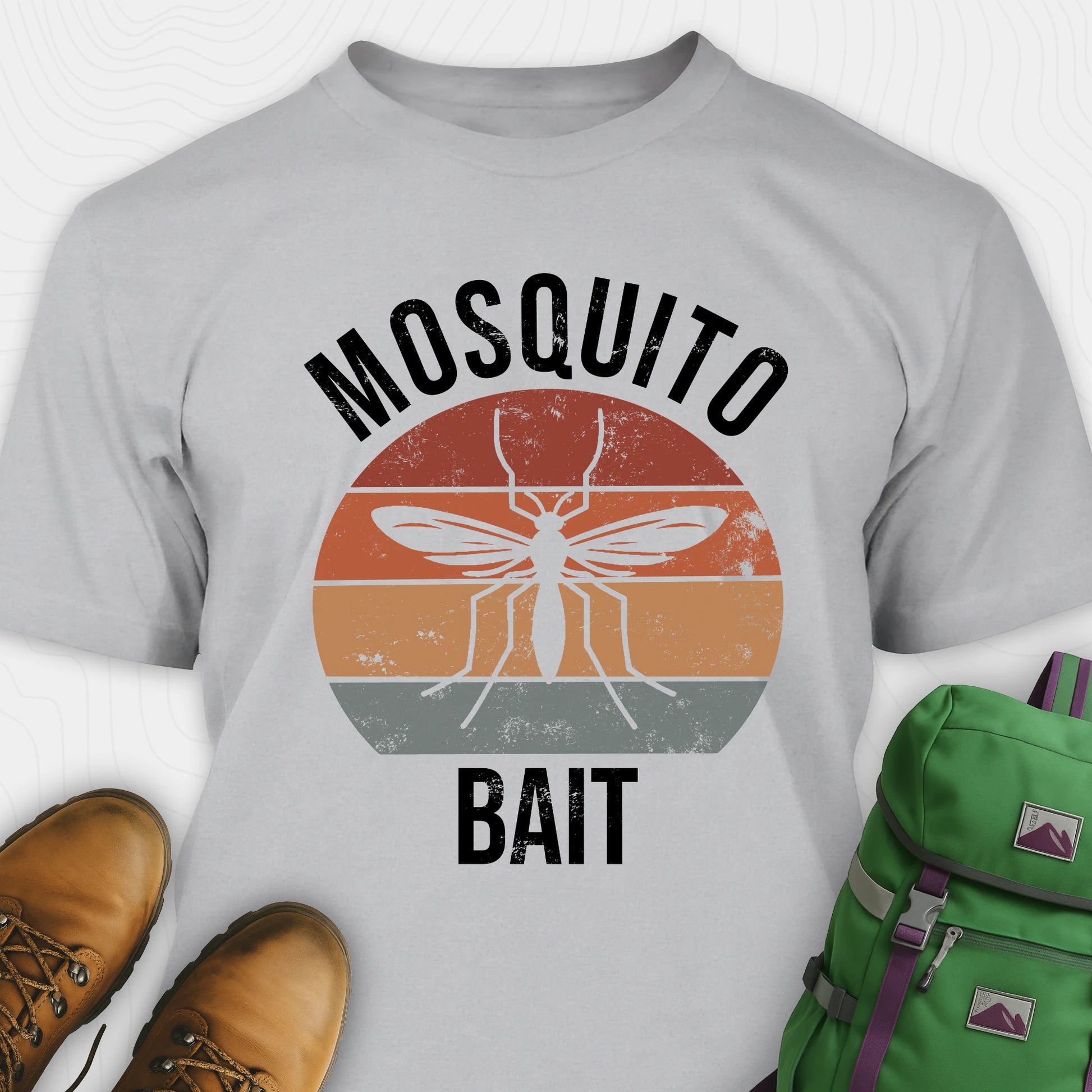 Grey mosquito shirt with 'Mosquito Bait' graphic design, brown boots, and green backpack on a white background
