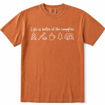 Yam rust-orange crewneck t-shirt with a white graphic print that reads 'Life is better at the campfire' above simple icons of a campfire, roasting marshmallow, mug, pine tree, and trailer.