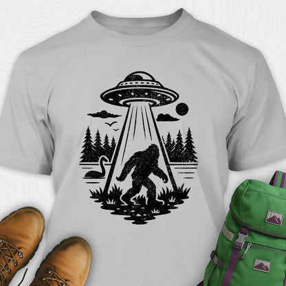 Grey monster shirt with bigfoot, forest scene, and ufo beam graphic