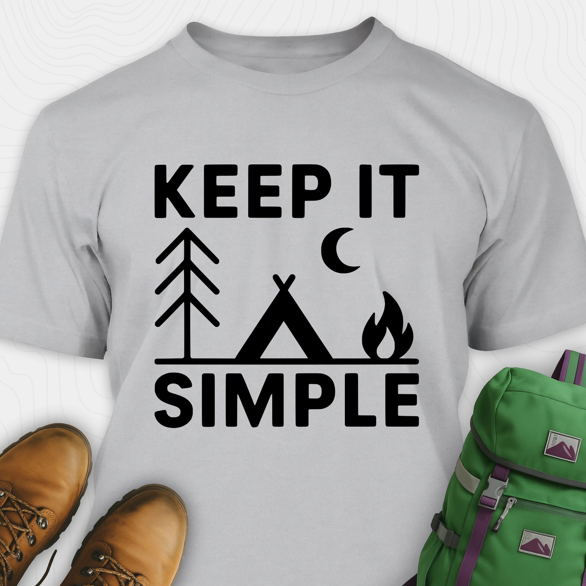Sport grey keep it simple camping t-shirt with tent and campfire graphic with boots, and a backpack on either side on a white background