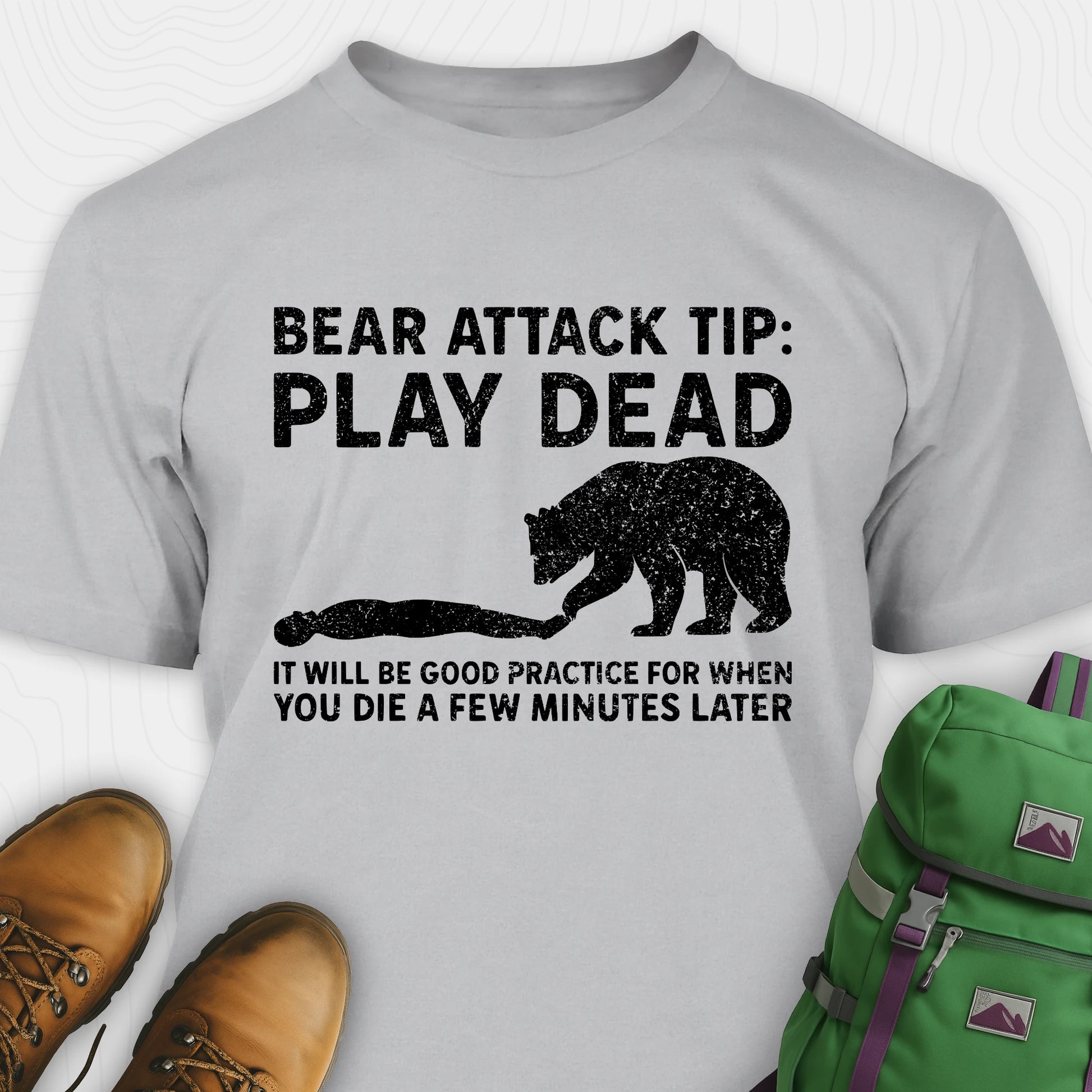 Gray bear tee shirt with bear attack tip graphic and text, paired with hiking boots and a green backpack.