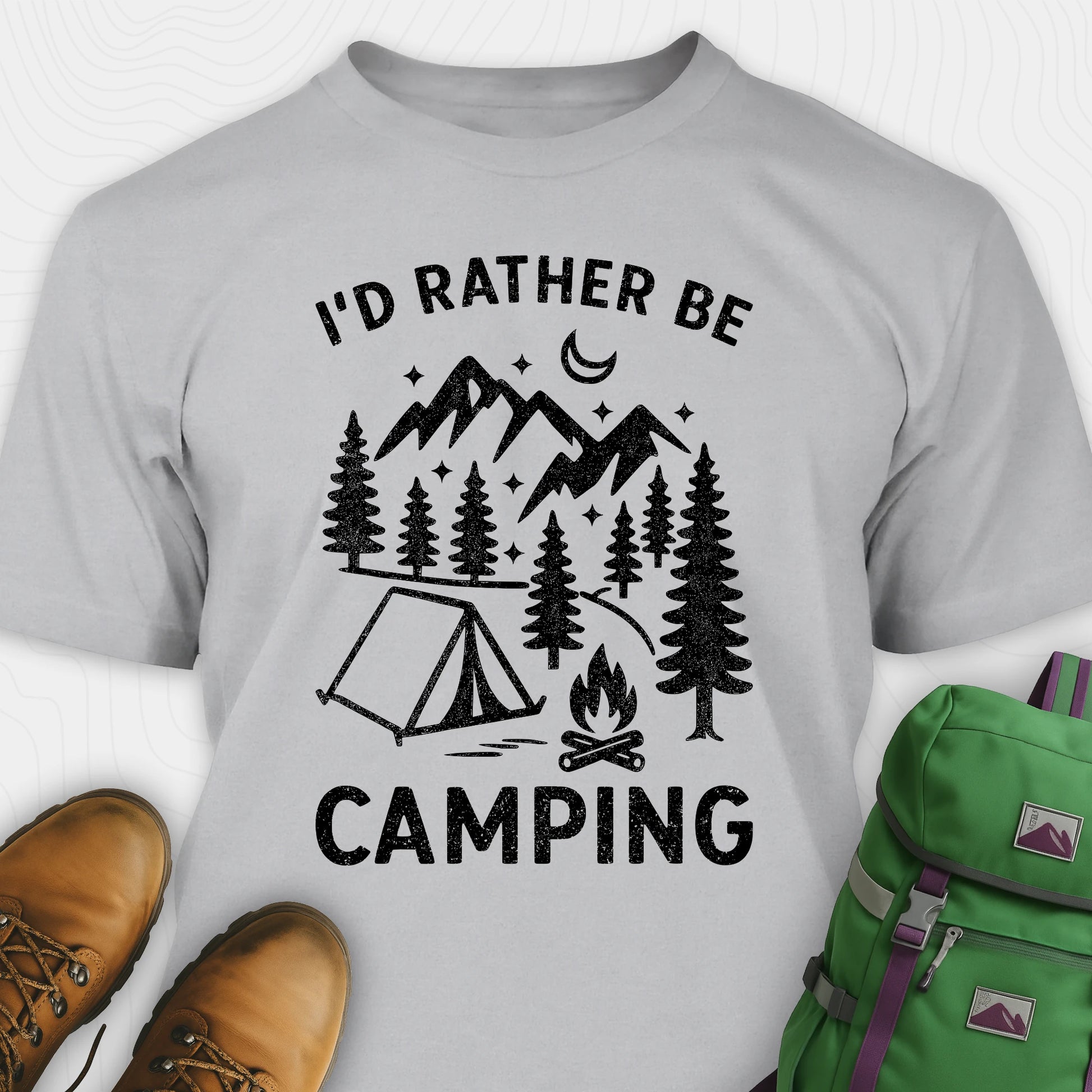 Gray t-shirt with 'I'd Rather Be Camping' design, brown boots, and green backpack on a white background