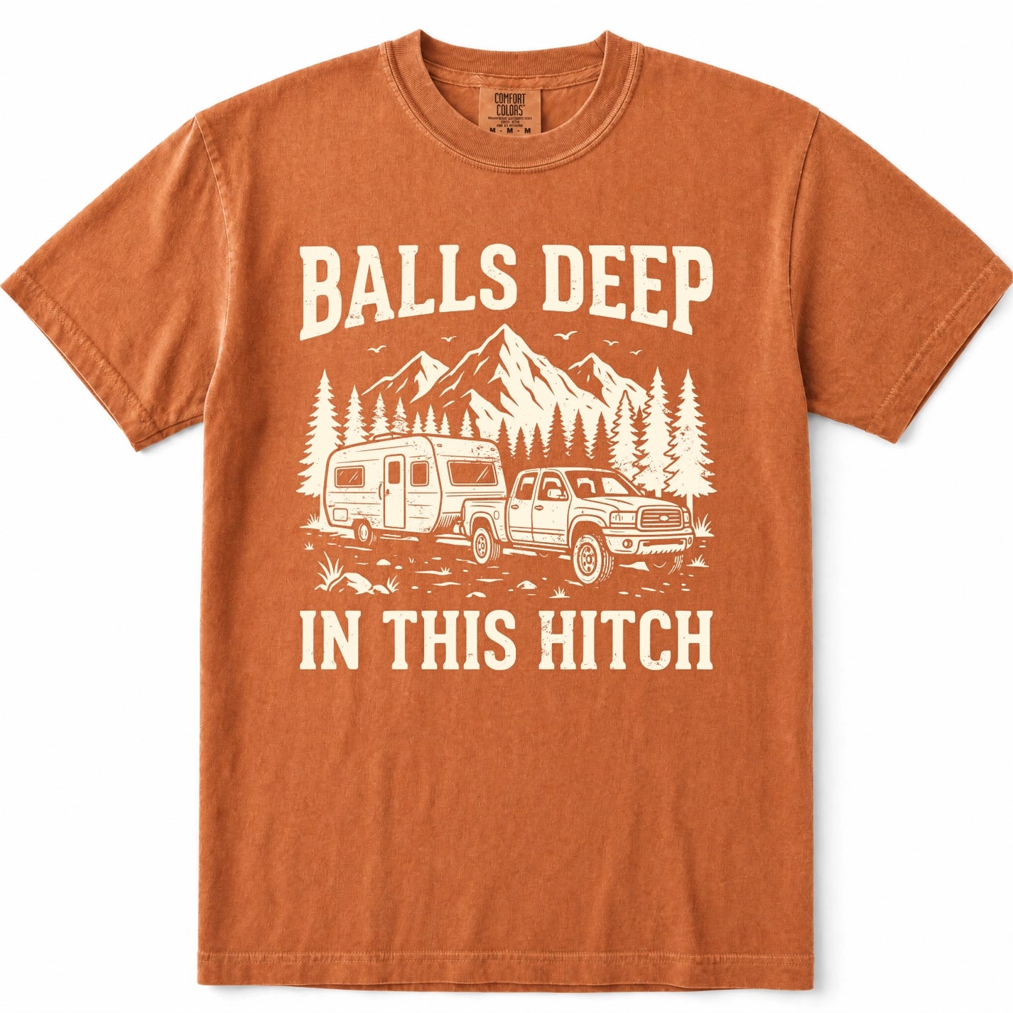 Yam rust-orange crewneck t-shirt with a cream-colored graphic print featuring a pickup truck towing a camper trailer, pine trees, and mountains, with the text 'BALLS DEEP IN THIS HITCH'.