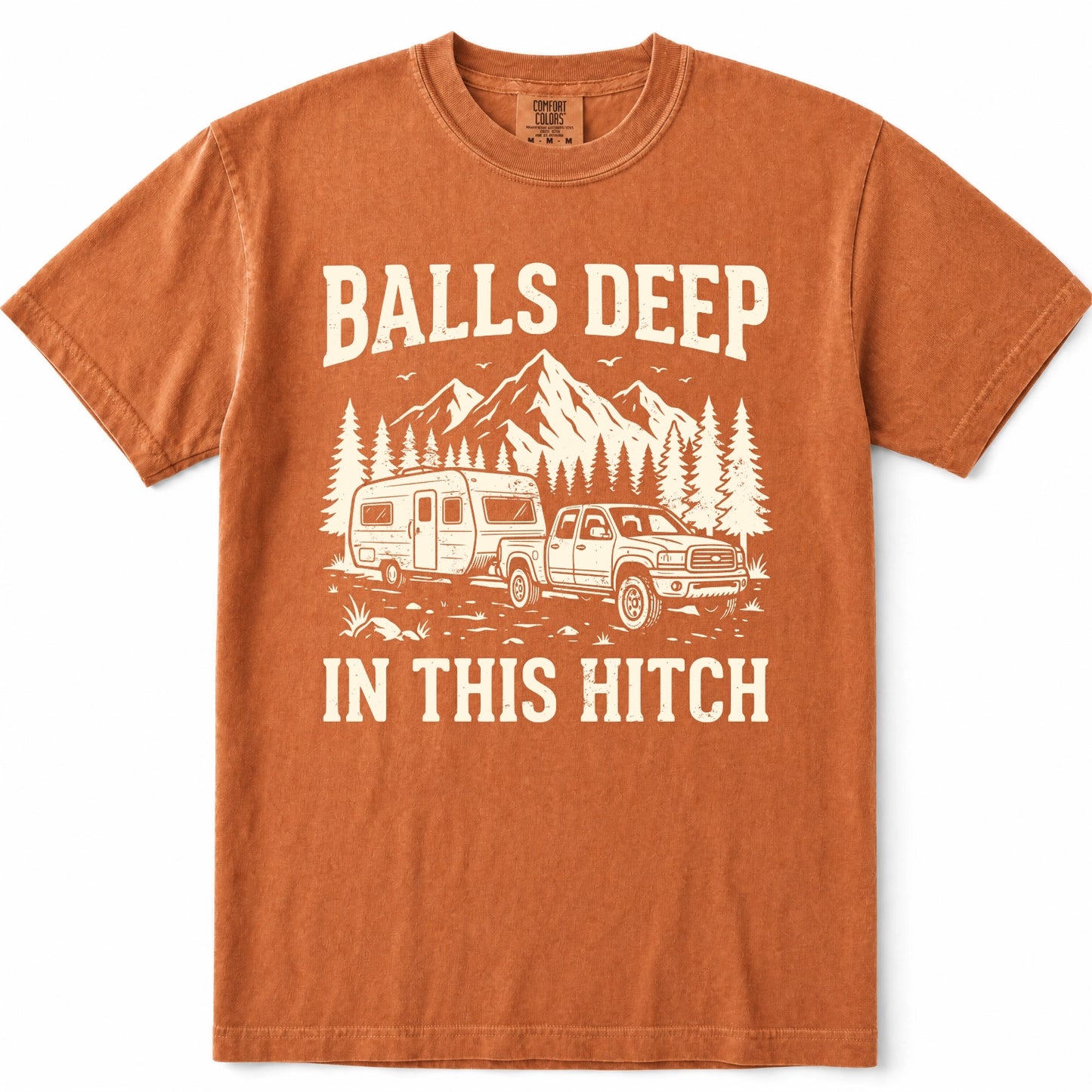Yam rust-orange crewneck t-shirt with a cream-colored graphic print featuring a pickup truck towing a camper trailer, pine trees, and mountains, with the text 'BALLS DEEP IN THIS HITCH'.