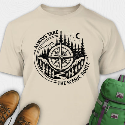 Natural always take the scenic route t-shirt with compass graphic and text, paired with hiking boots and a green backpack.