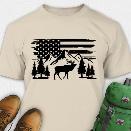 Sand deer shirt with a black graphic of a deer, mountains, and trees on an American flag design, paired with brown boots and a green backpack.