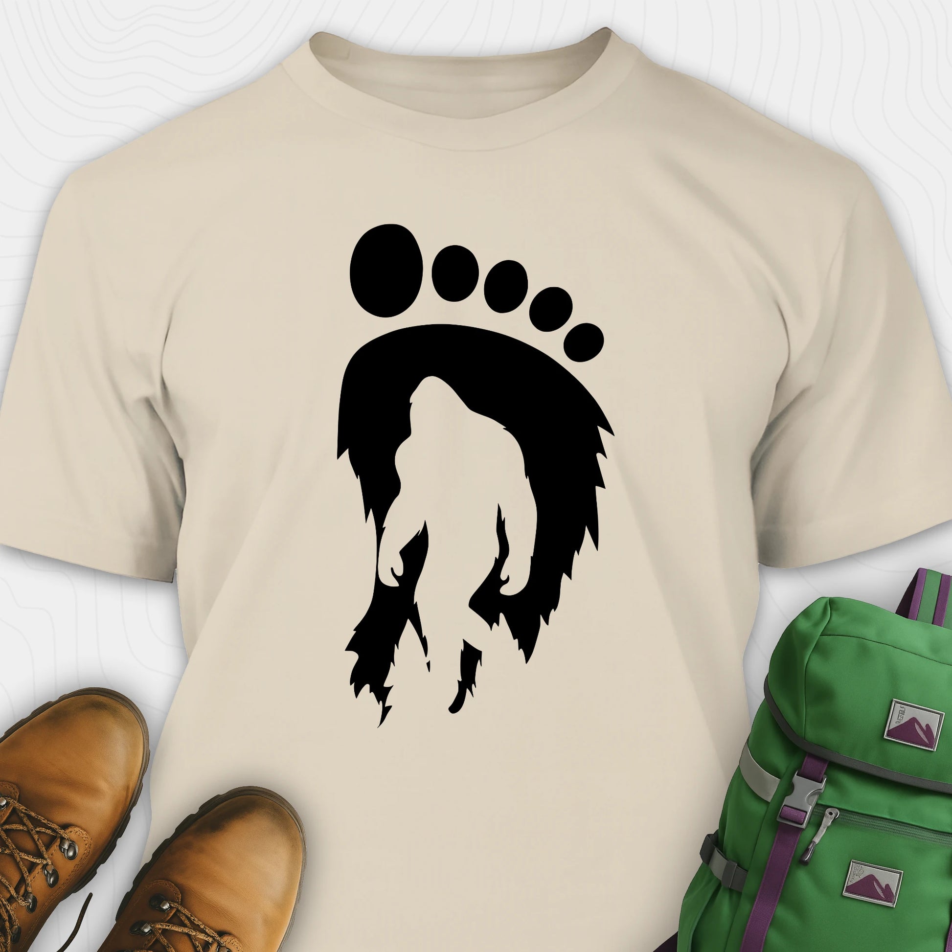 Sand bigfoot t-shirt with cryptid themed footprint graphic and sasquatch silhouette