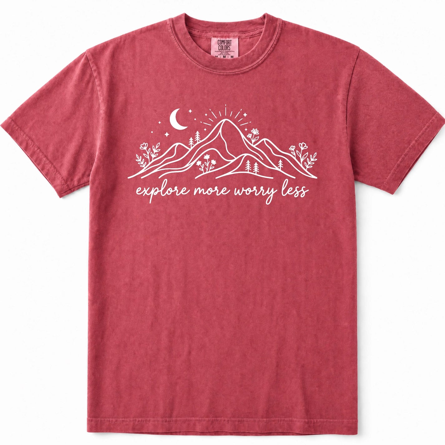 Crimson short-sleeve crewneck t-shirt in a washed, heathered red color, featuring a white graphic of mountains, a crescent moon, stars, and the text 'explore more worry less' printed across the chest.